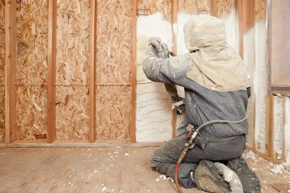Contractor applying spray foam insulation during basement insulation installation