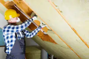 Contractor installing batt insulation between attic rafters