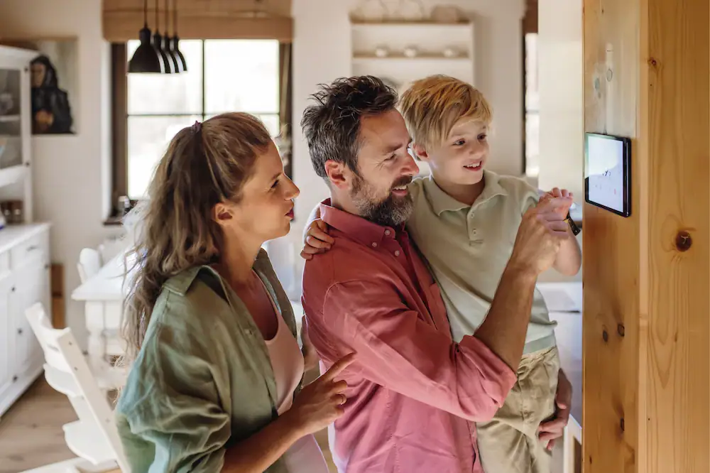 Family adjusting a wall-mounted thermostat at home