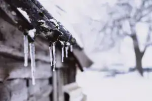 Ice buildup and icicles along the edge of a snow-covered roof