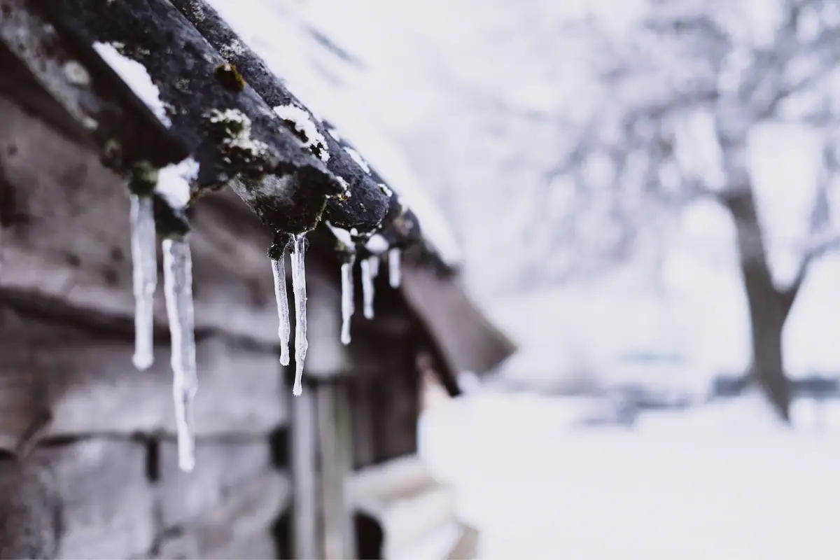 Ice buildup and icicles along the edge of a snow-covered roof