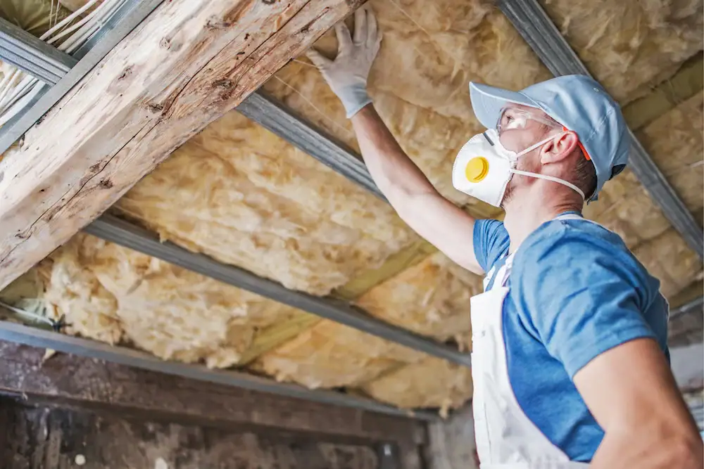 Professional inspecting insulation and roof framing inside an attic