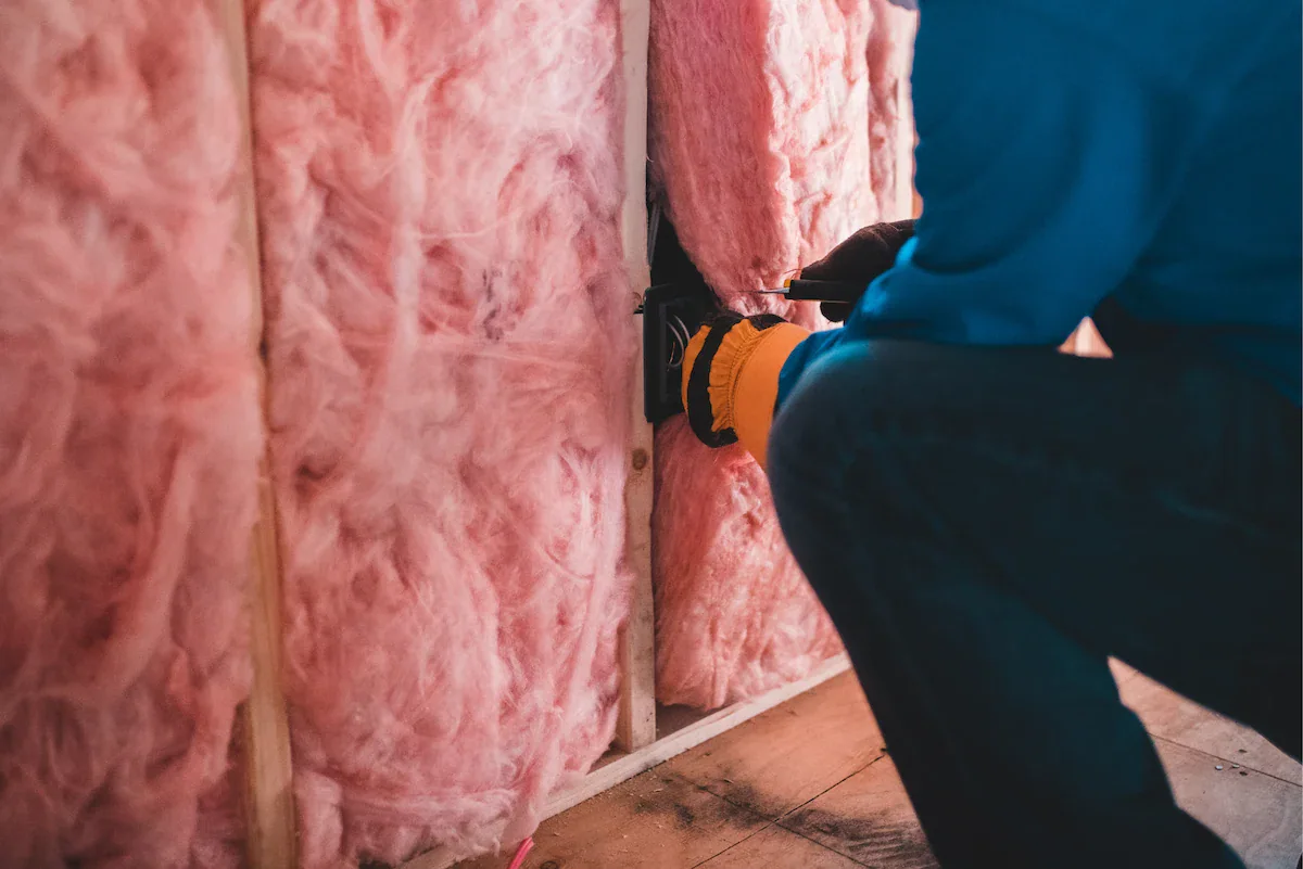 Insulation being installed between wooden wall studs